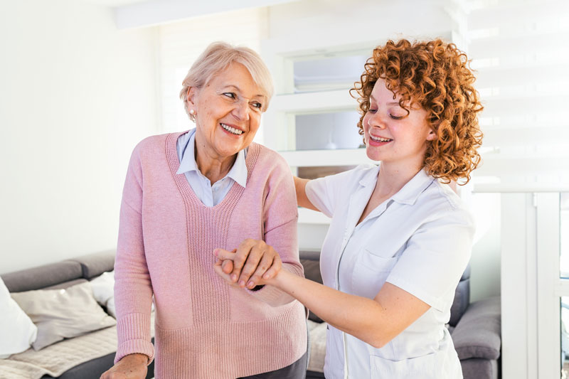 Photo of an elderly woman being helped by a caregiver.