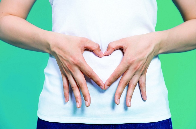 Person with hand heart symbol over stomach